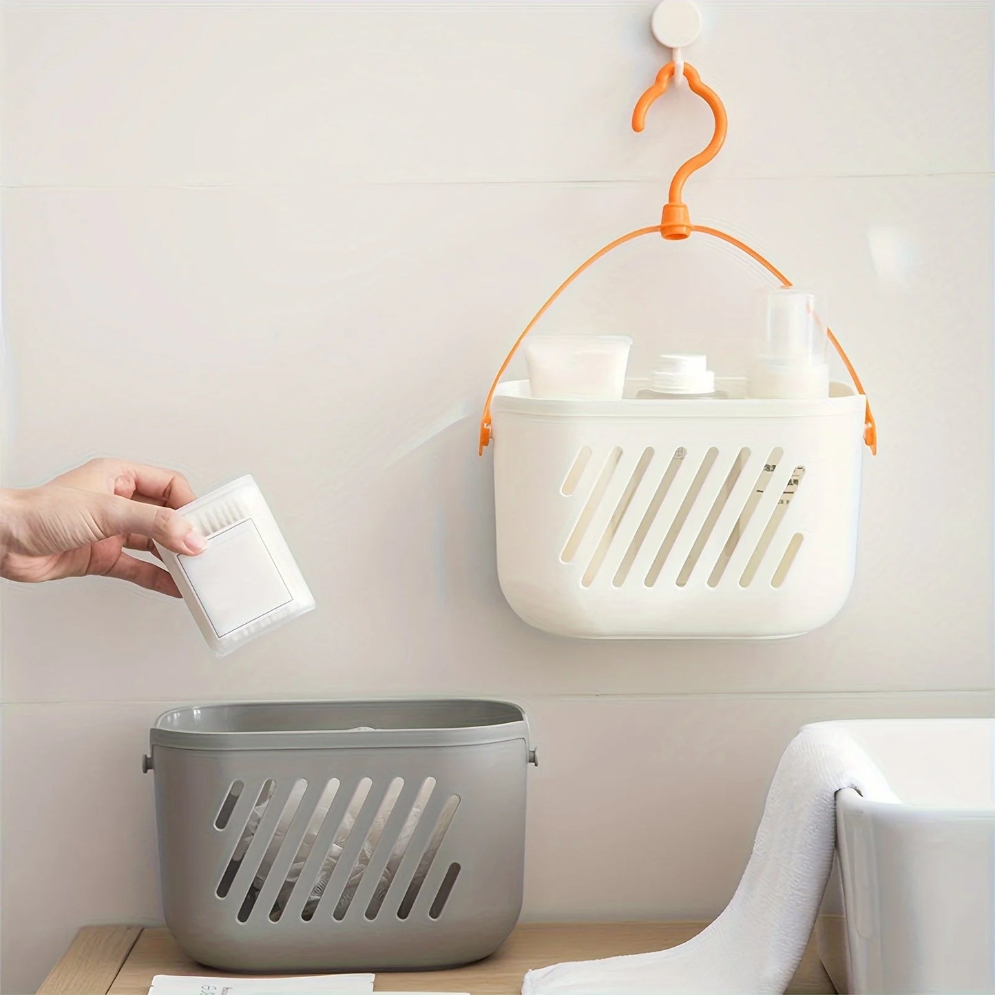 White and grey hanging storage baskets with orange hook mounted on wall for pantry and bathroom organization