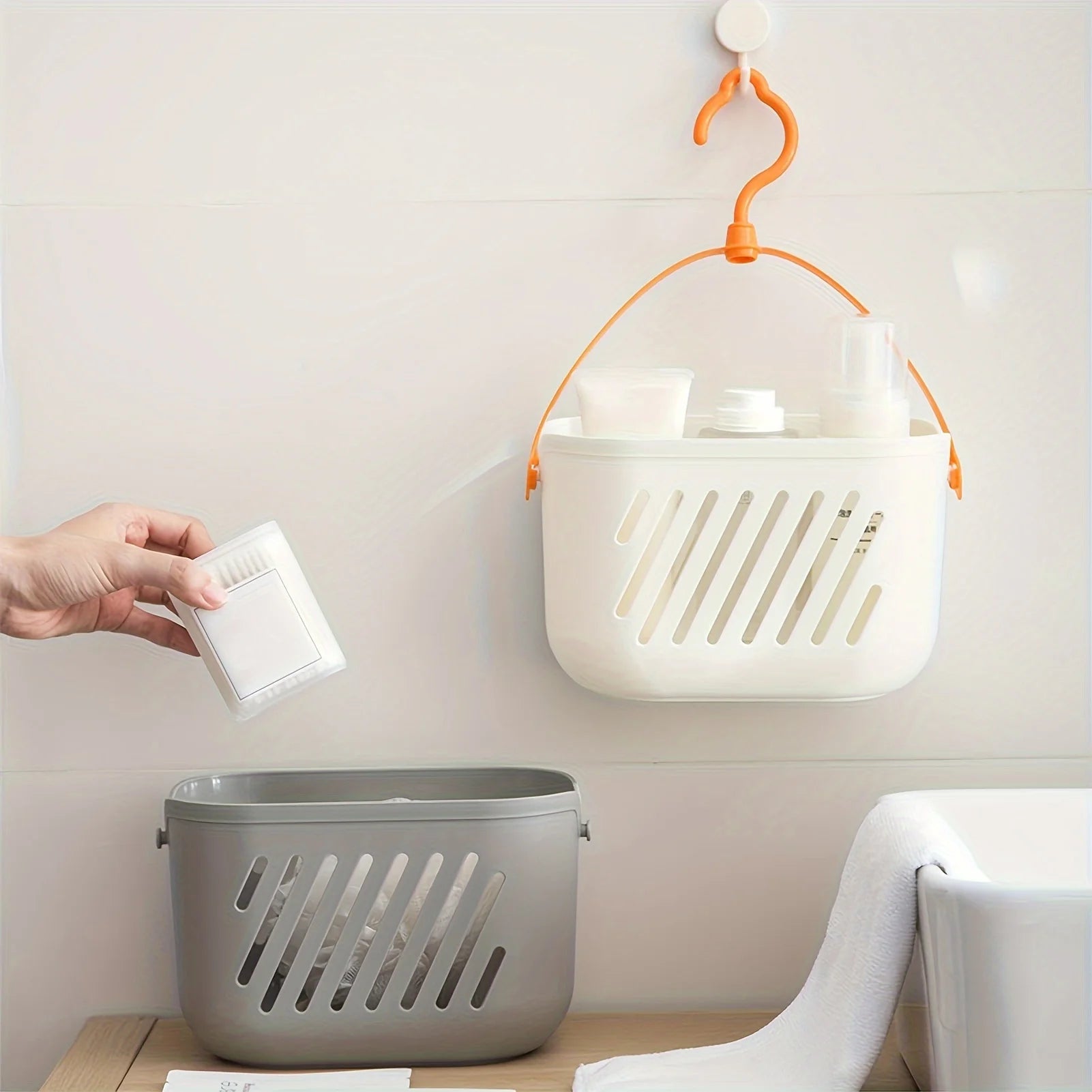 White and grey hanging storage baskets with orange hook mounted on wall for pantry and bathroom organization