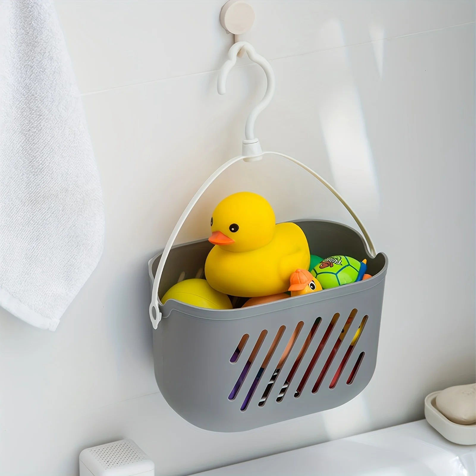 Grey hanging storage basket holding bath toys and rubber duck, wall-mounted in bathroom