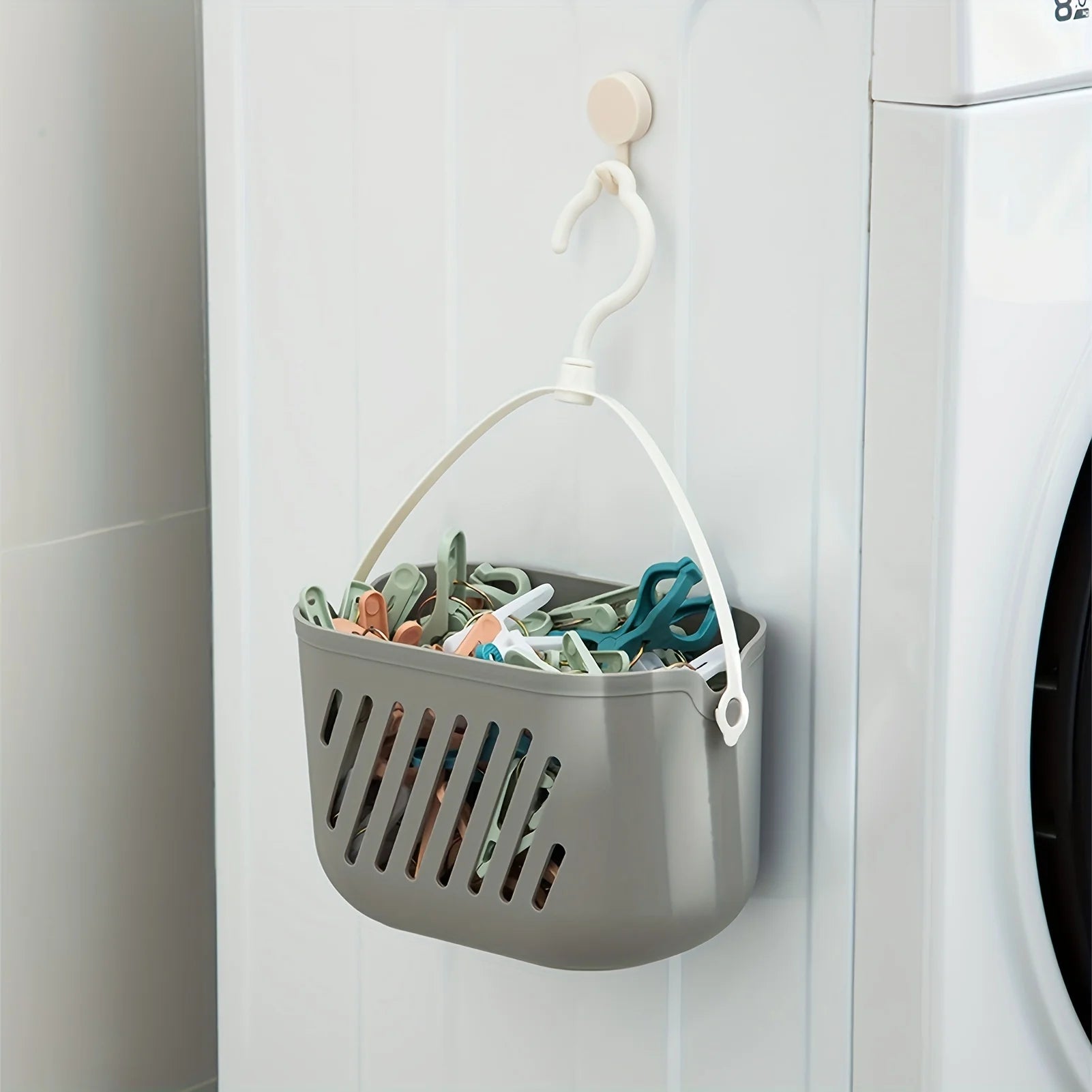 Grey hanging storage basket with clothespins mounted next to washing machine for laundry room organization