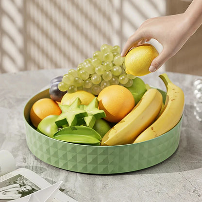 Green lazy susan kitchen organizer used as fruit bowl displaying grapes, bananas, oranges and tropical fruits