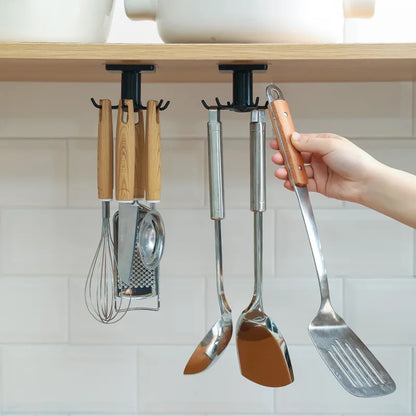 Rotating wall-mounted kitchen hooks rack holding utensils, spatulas, and a whisk under a cabinet shelf